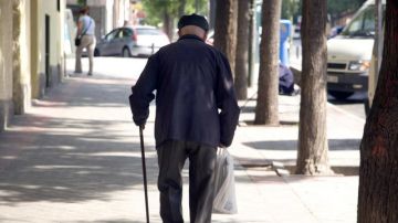 Un jubilado camina en una calle. 