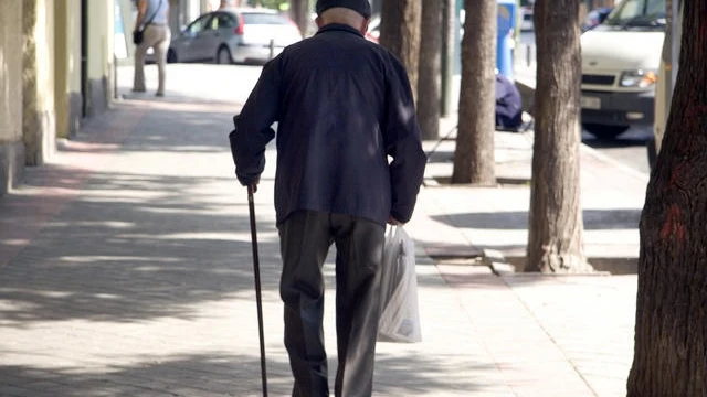 Un jubilado camina en una calle. 