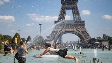 Personas refrescándose en la fuente de la Plaza del Trocadero, frente a la Torre Eiffel en París