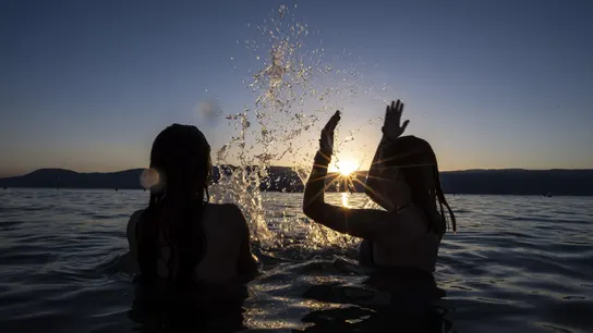 Dos adolescentes disfrutan de la puesta de sol en el agua del Lago de Neuchatel Dos adolescentes disfrutan de la puesta de sol en el agua del Lago de Neuchatel