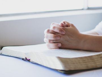Una persona rezando sobre una Biblia Una persona rezando sobre una Biblia