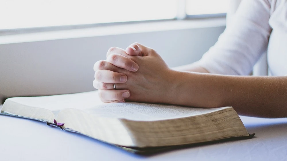 Una persona rezando sobre una Biblia.