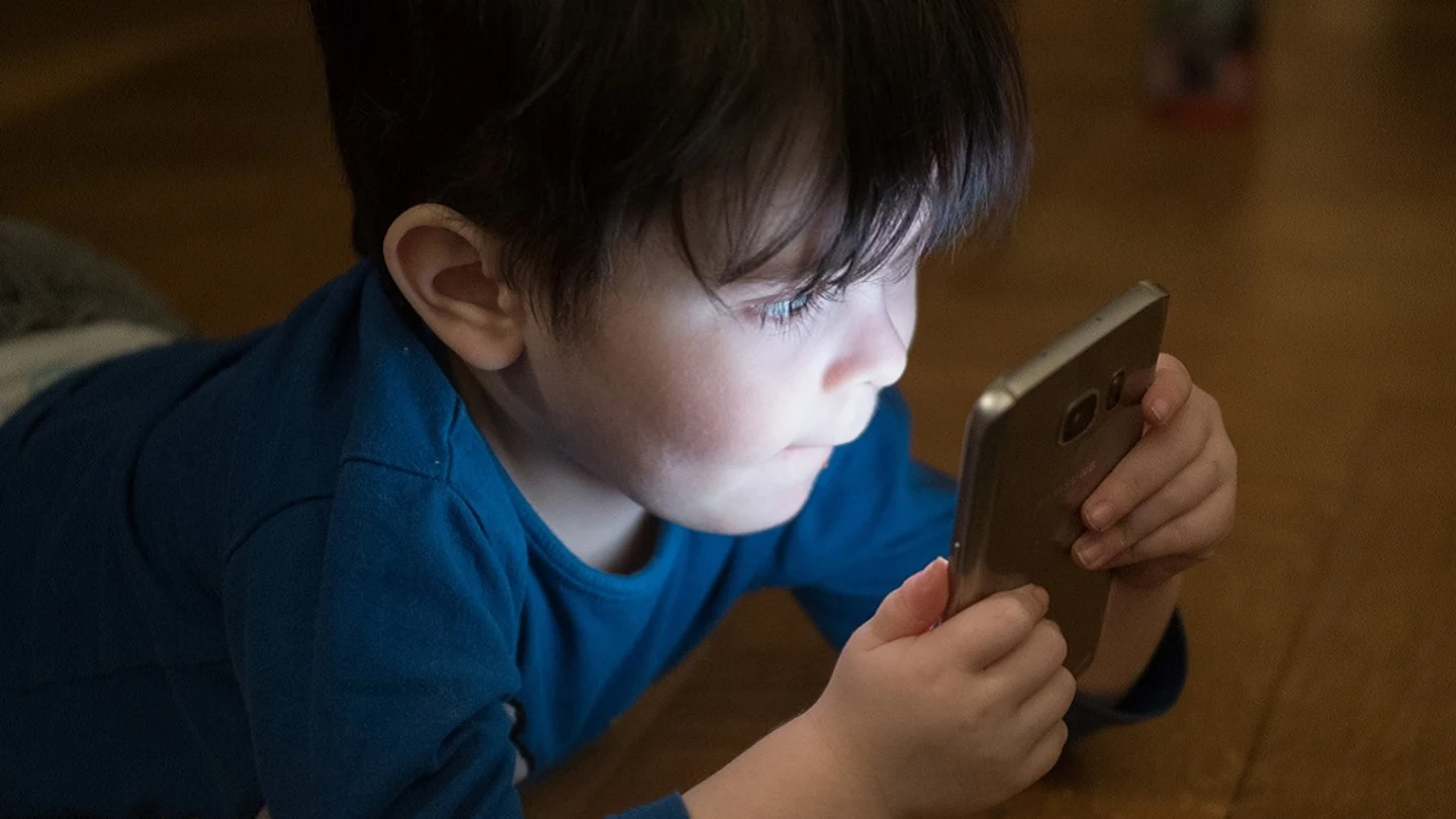 Un niño utiliza un teléfono móvil en una imagen de archivo. Un niño utiliza un teléfono móvil en una imagen de archivo.