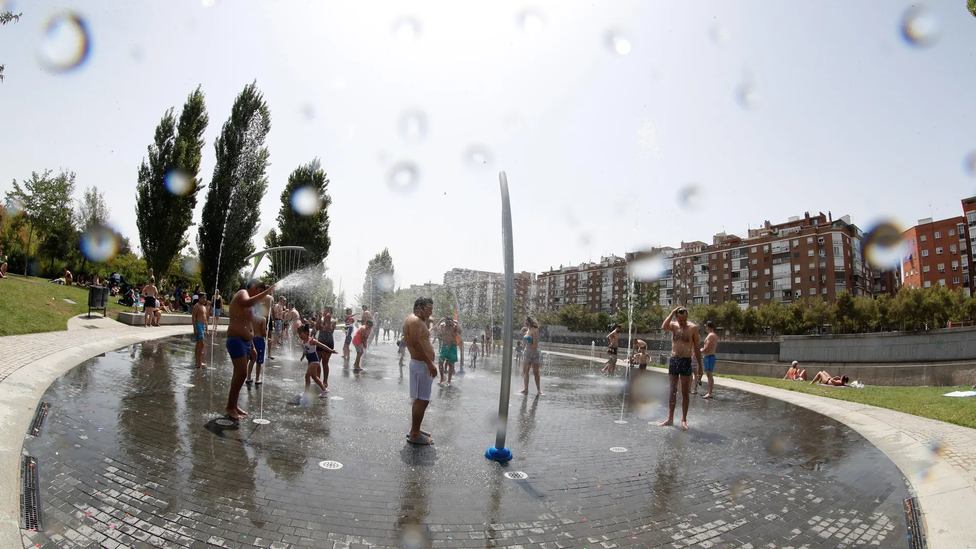 Grupos de personas se refrescan en la fuentes verticales de Madrid Río