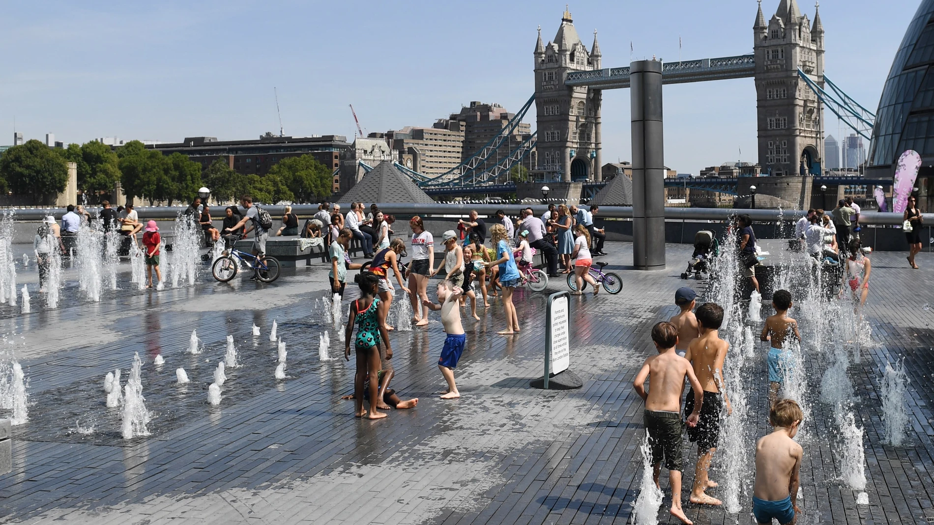 Un grupo de niños combaten la ola de calor mojándose en una fuente frente al Puente de la Torre de Londres