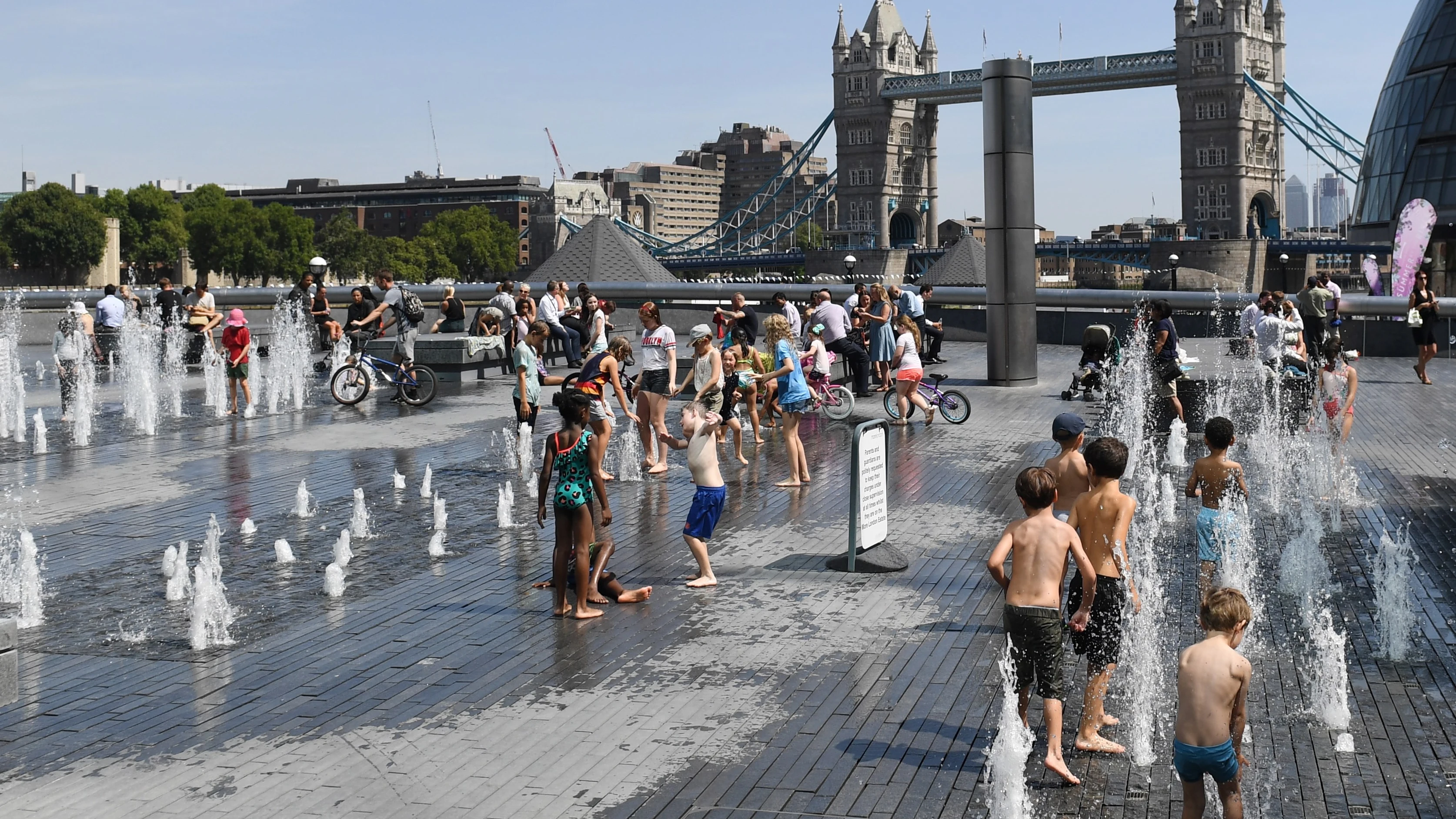 Un grupo de niños combaten la ola de calor mojándose en una fuente frente al Puente de la Torre de Londres