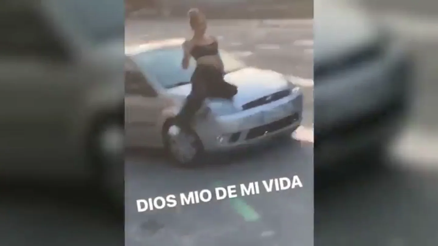 Un conductor temerario transporta a una mujer en el capó de su coche Un conductor temerario transporta a una mujer en el capó de su coche