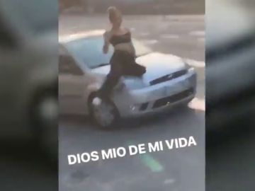 Un conductor temerario transporta a una mujer en el capó de su coche