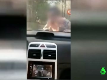 Se graba conduciendo con una persona sobre el capó de su coche Se graba conduciendo con una persona sobre el capó de su coche