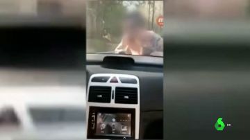 Se graba conduciendo con una persona sobre el capó de su coche