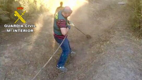 Agente de la Guardia Civil desenterrando la manguera enganchada al oleoducto.