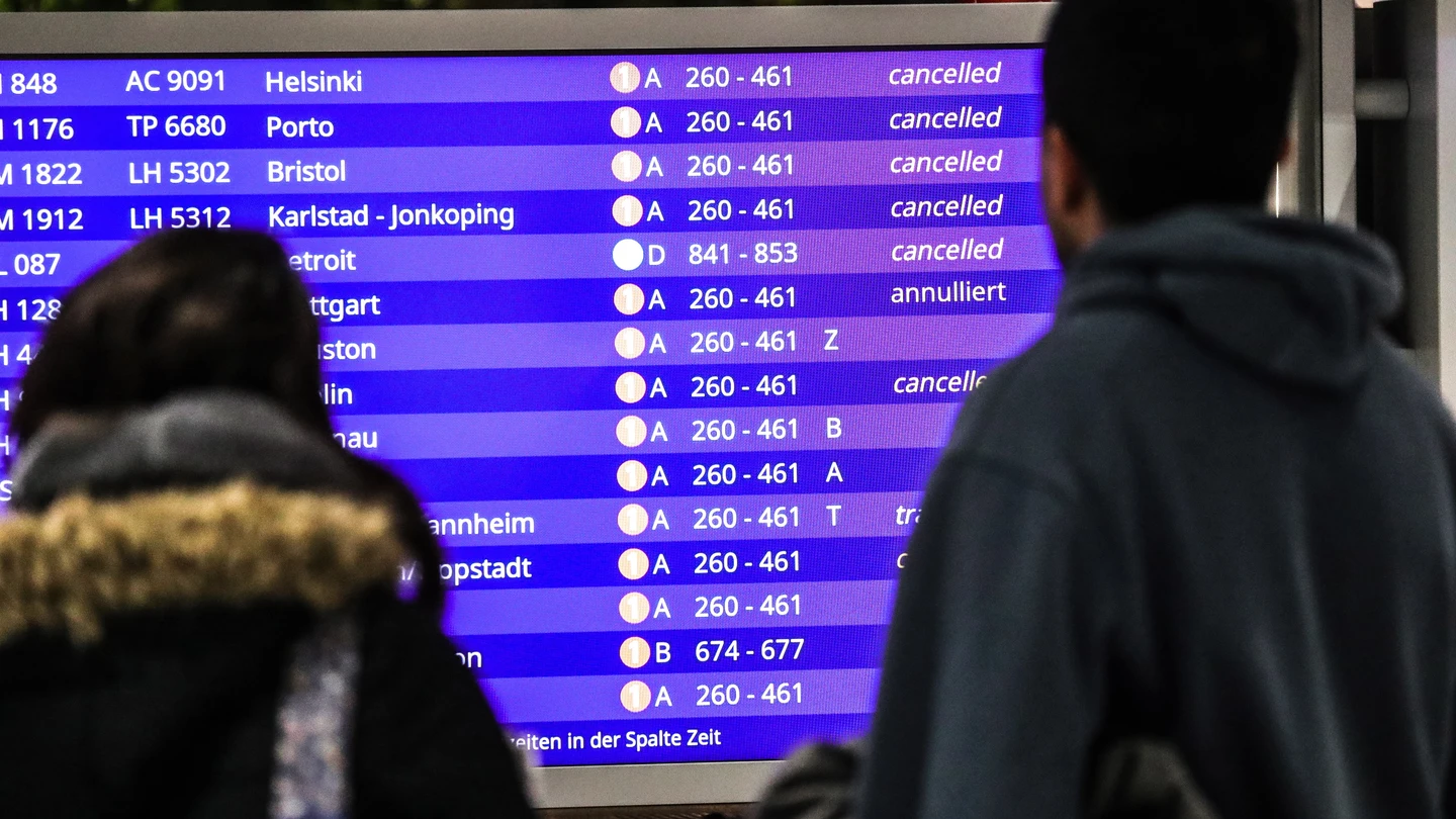 Pasajeros miran los vuelos cancelados en una pantalla informativa Pasajeros miran los vuelos cancelados en una pantalla informativa