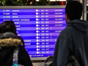 Pasajeros miran los vuelos cancelados en una pantalla informativa Pasajeros miran los vuelos cancelados en una pantalla informativa