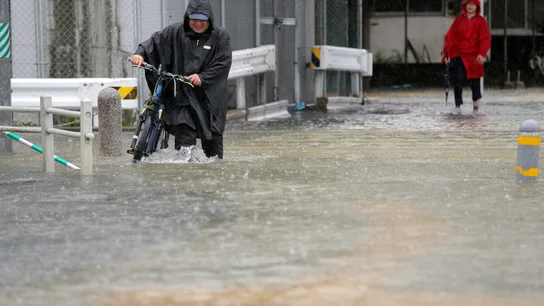 Imagen de un hombre circulando por una calle inundada. Imagen de un hombre circulando por una calle inundada.