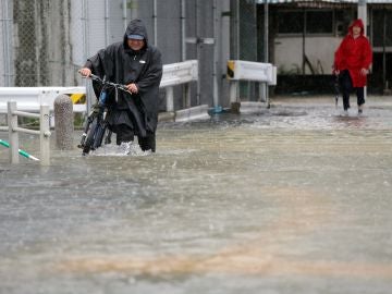 Imagen de un hombre circulando por una calle inundada. Imagen de un hombre circulando por una calle inundada.