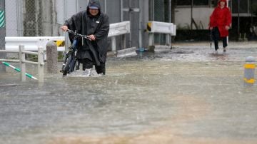Imagen de un hombre circulando por una calle inundada.