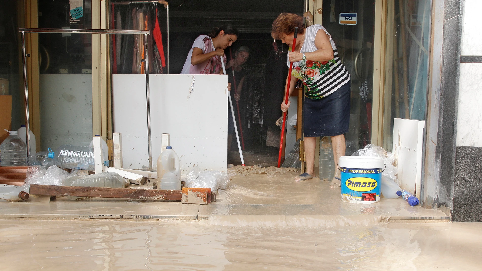 Vecinos de Orihuela limpian sus casas y negocios anegados por la avenida de agua povocada por el desbordamiento del río Segura tras la gota fría.