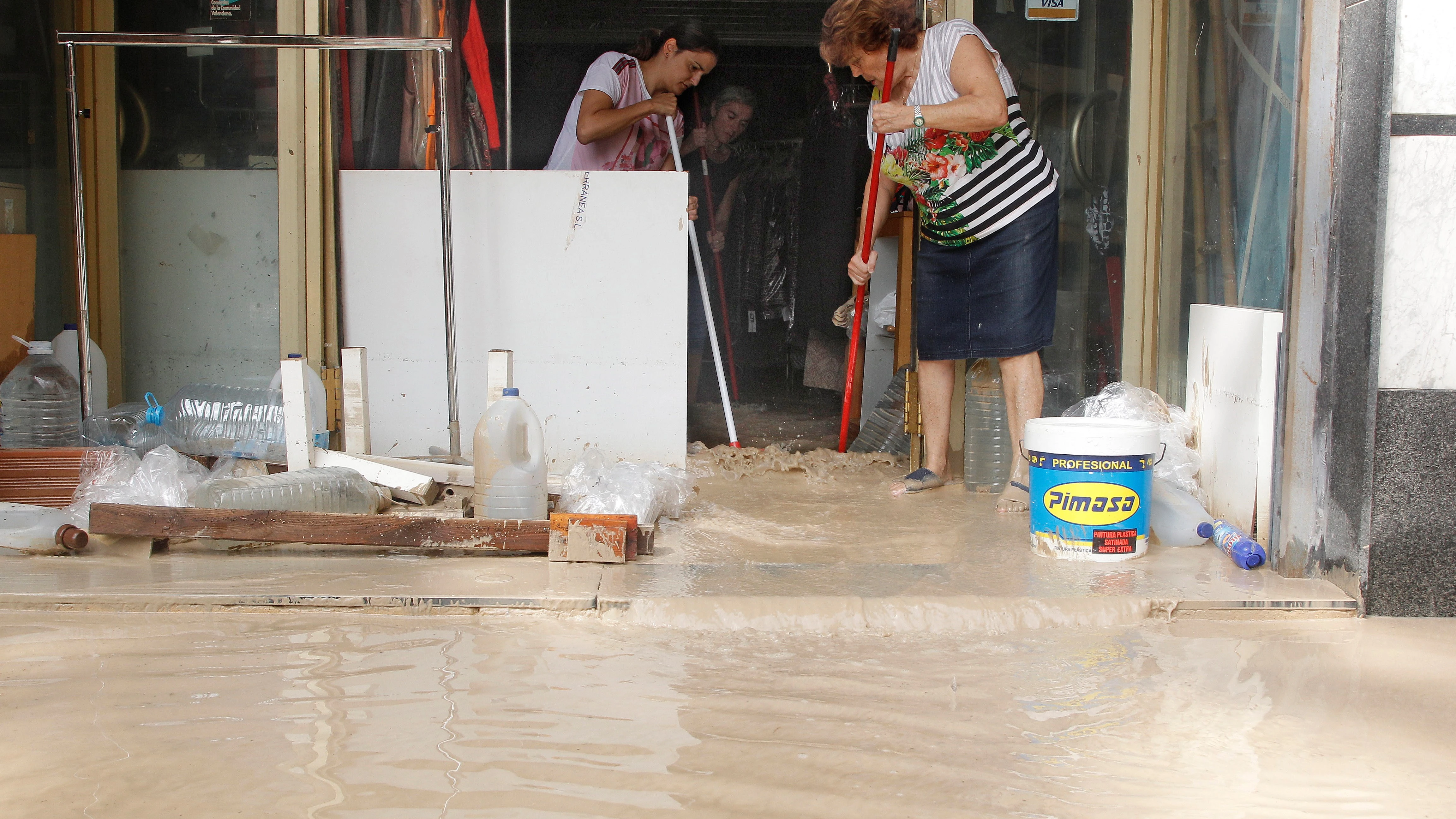 Vecinos de Orihuela limpian sus casas y negocios anegados por la avenida de agua povocada por el desbordamiento del río Segura tras la gota fría.