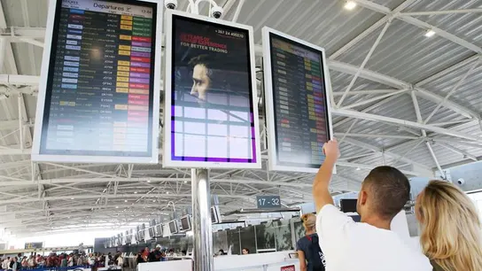 Pasajeros buscan información sobre un vuelo en el panel de un aeropuerto Pasajeros buscan información sobre un vuelo en el panel de un aeropuerto