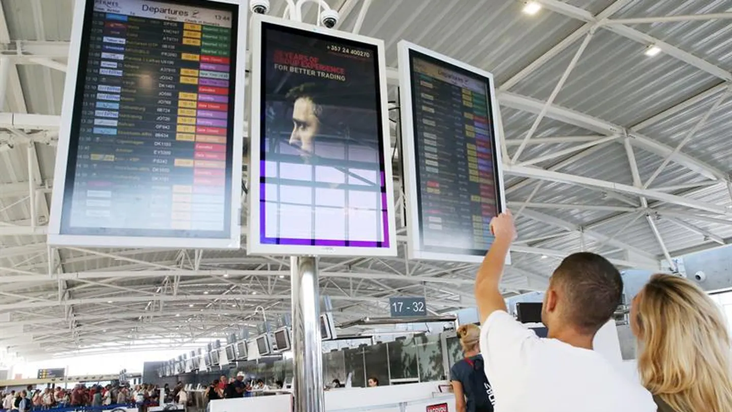 Pasajeros buscan información sobre un vuelo en el panel de un aeropuerto Pasajeros buscan información sobre un vuelo en el panel de un aeropuerto