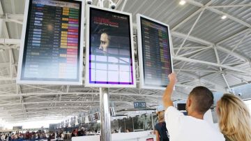 Pasajeros buscan información sobre un vuelo en el panel de un aeropuerto