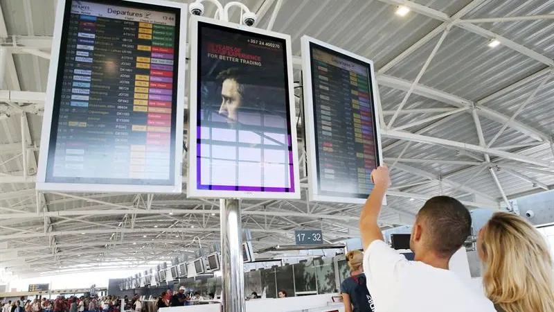 Pasajeros buscan información sobre un vuelo en el panel de un aeropuerto