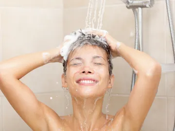Mujer frotándose el pelo en la ducha Mujer frotándose el pelo en la ducha