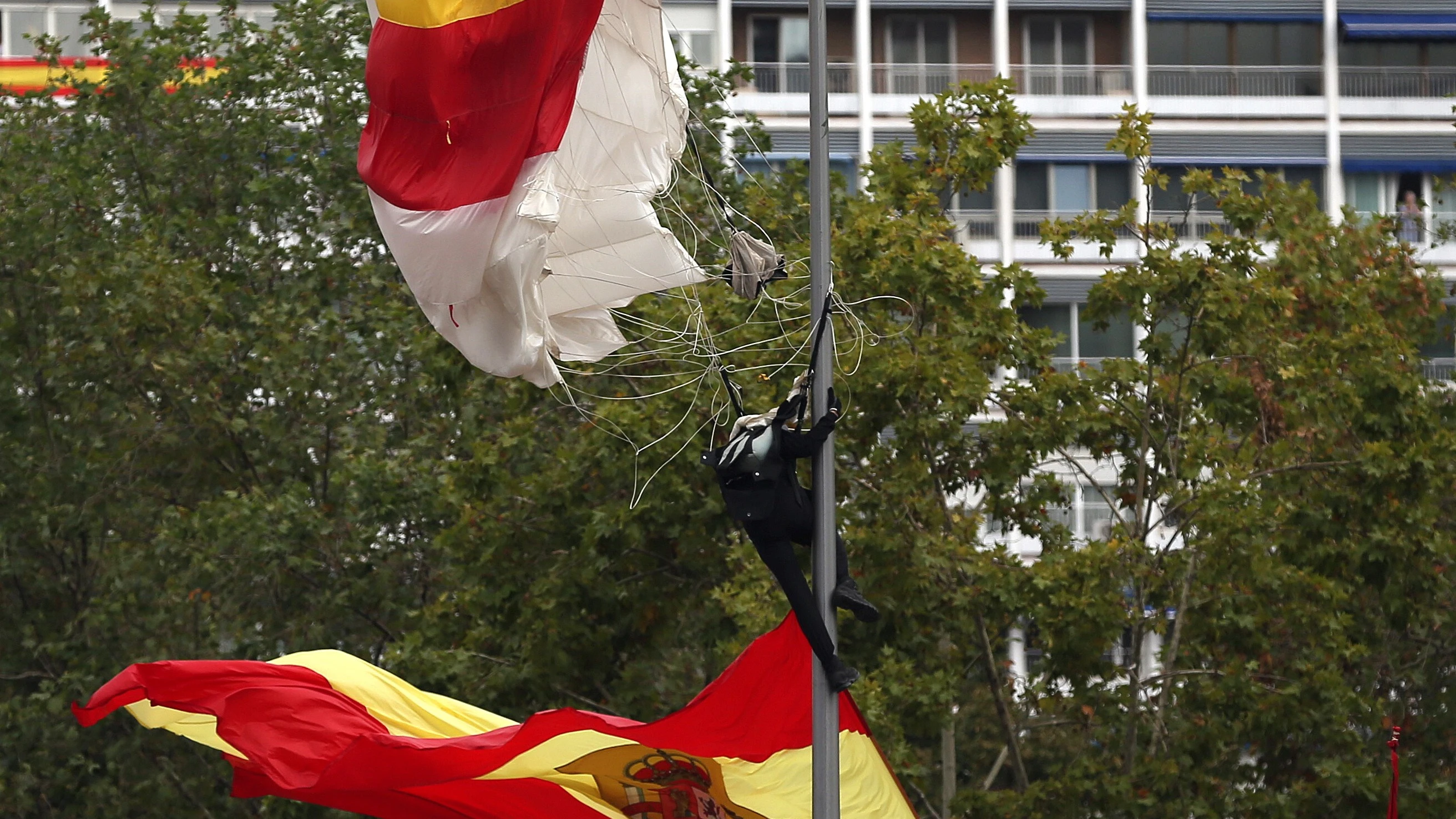 El paracaidista que descendía portando la bandera, en la farola en la que se enganchó 