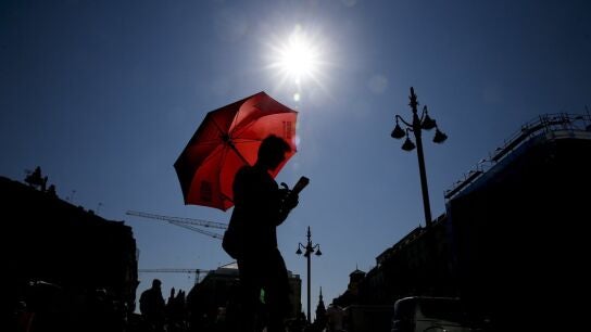 Un joven se protege del sol con un paraguas (Archivo)