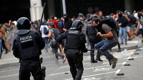 Miembros de los Mossos d'Esquadra cargan contra los centenares de personas que se agolpan ante el Aeropuerto del Prat Miembros de los Mossos d'Esquadra cargan contra los centenares de personas que se agolpan ante el Aeropuerto del Prat