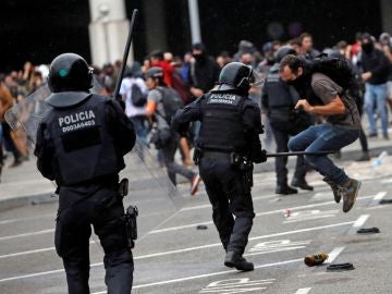 Miembros de los Mossos d'Esquadra cargan contra los centenares de personas que se agolpan ante el Aeropuerto del Prat Miembros de los Mossos d'Esquadra cargan contra los centenares de personas que se agolpan ante el Aeropuerto del Prat