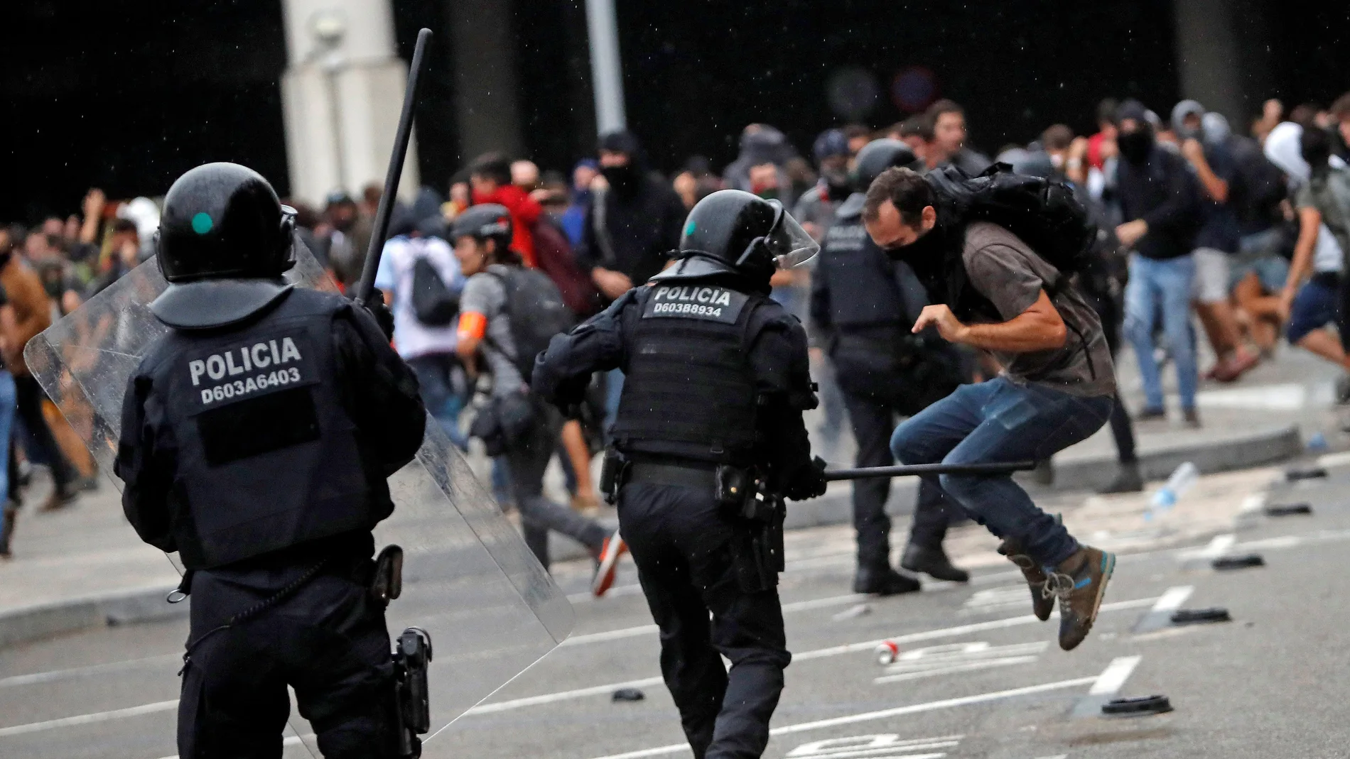 Miembros de los Mossos d'Esquadra cargan contra los centenares de personas que se agolpan ante el Aeropuerto del Prat