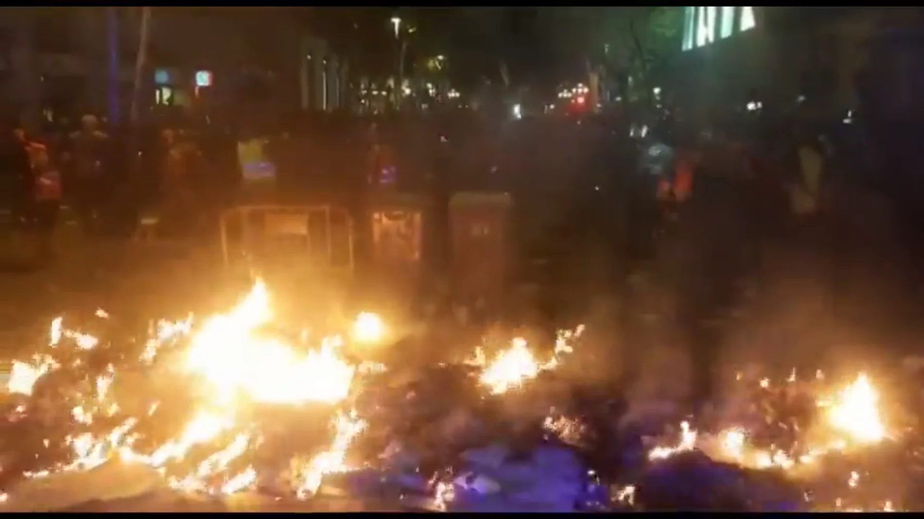 Manifestantes alientan con cartones el fuego de una barricada frente a la Delegación del Gobierno de Barcelona