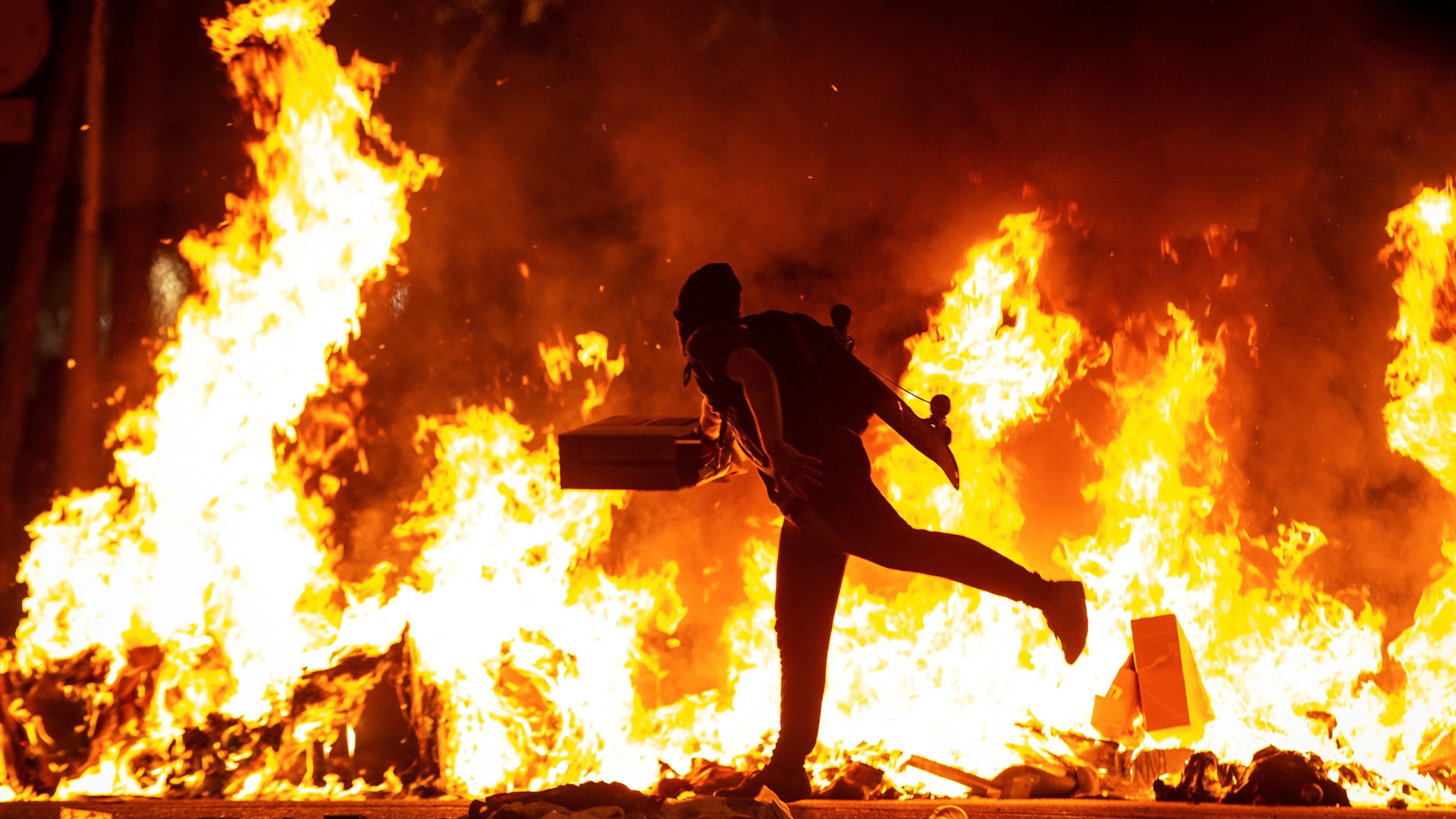 Un manifestante echa al fuego un cartón junto a la Delegación del Gobierno en Barcelona