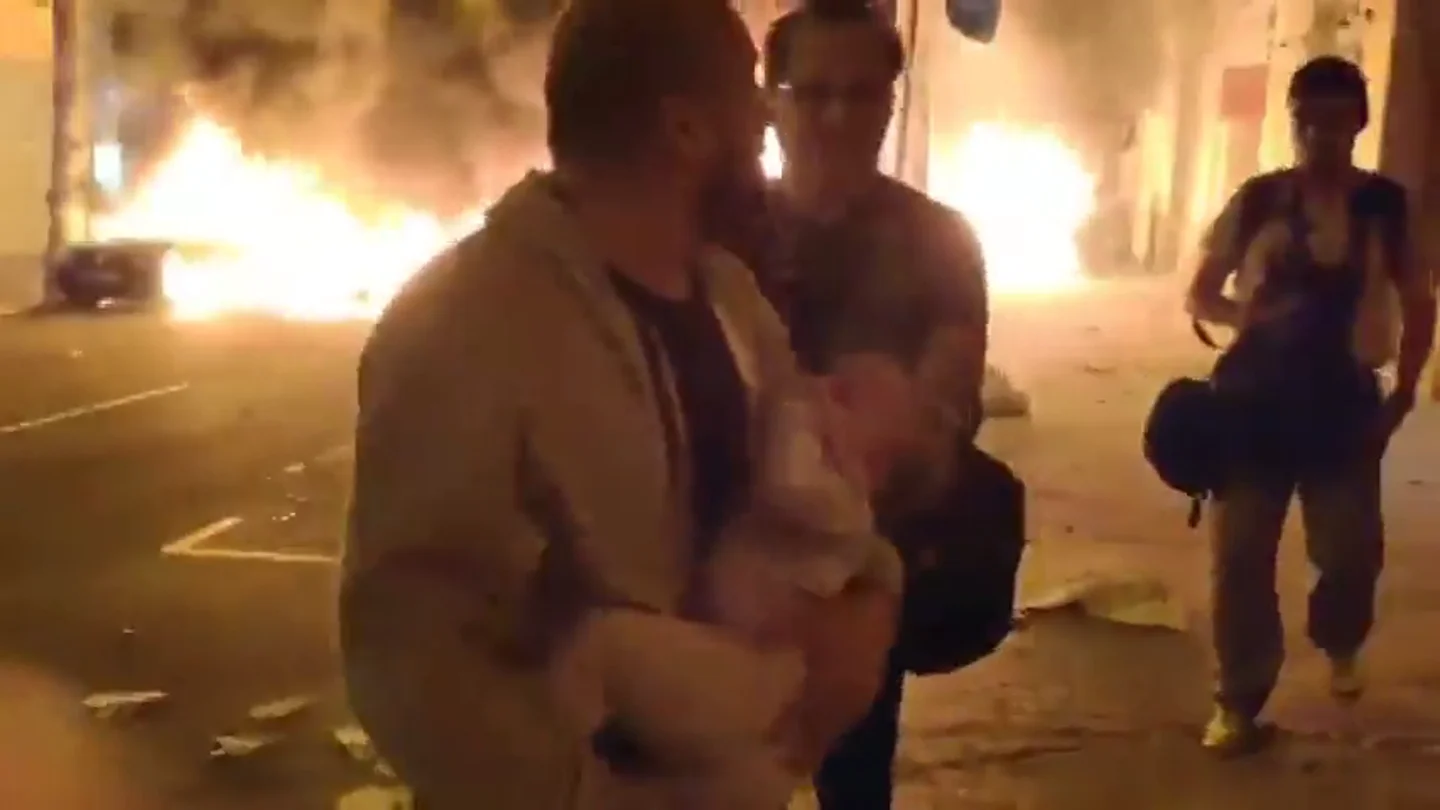 Un padre huye con su bebé en brazos de las llamas de las barricadas en Barcelona Un padre huye con su bebé en brazos de las llamas de las barricadas en Barcelona