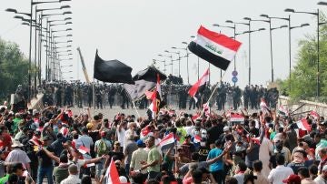 Manifestantes iraquíes portan banderas nacionales mientras gritan consignas