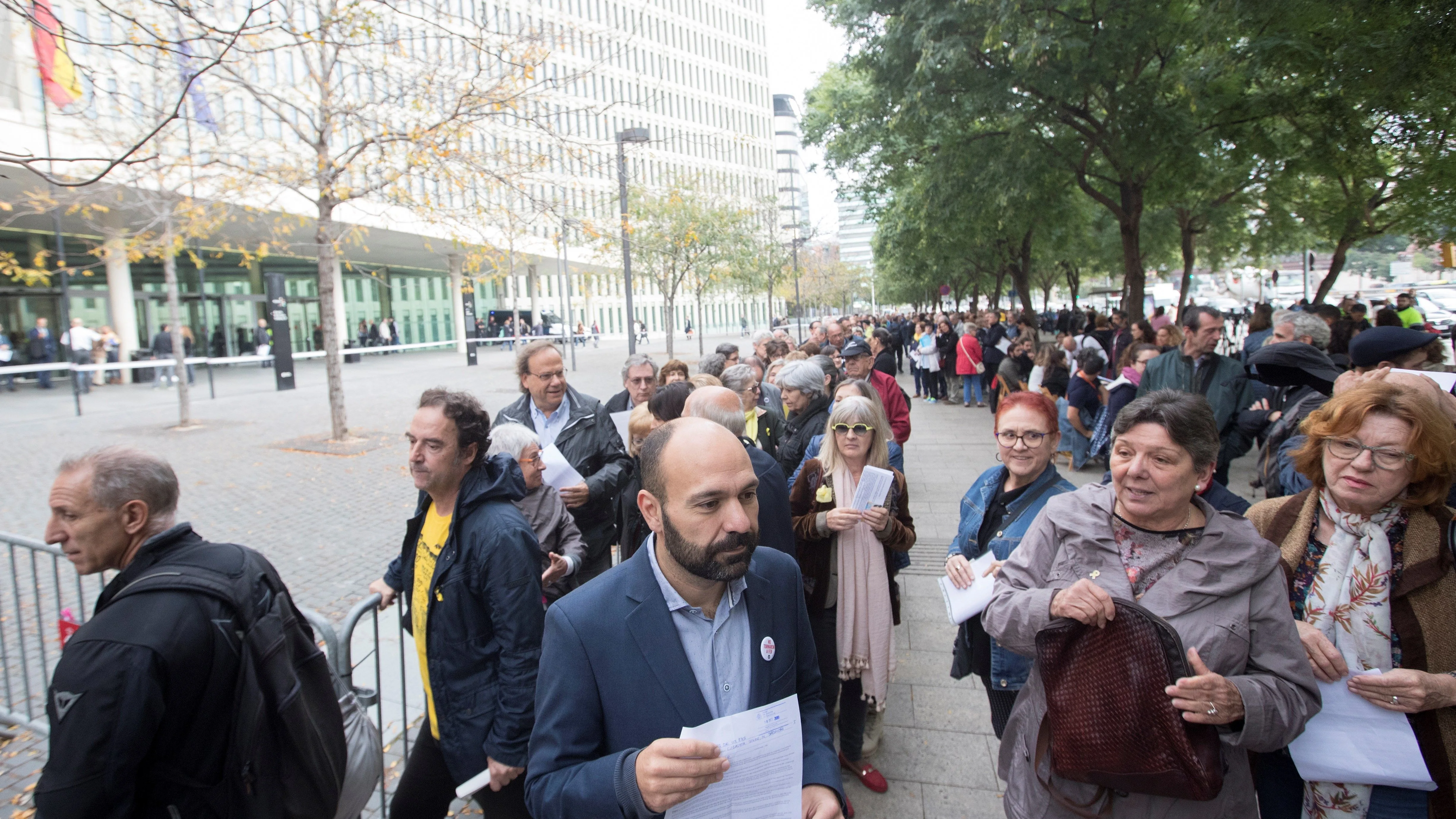 El vicepresidente de Omnium Cultural, Marcel Mauri (c), acompañado por la activista social, Gabriela Serra (d), esperan frente a la Ciudad de la Justicia, para entregar la documentación de autoinculpación en el marco de una campaña impulsada por la entidad.