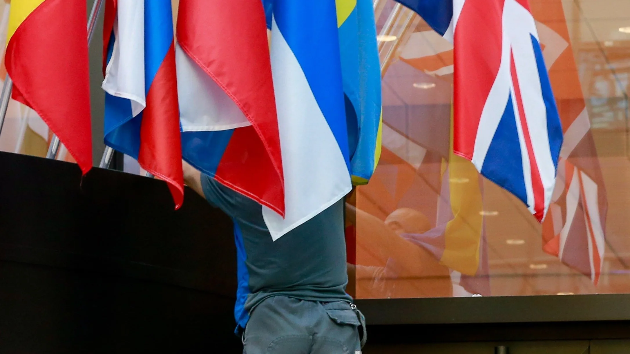 Un trabajador cuelga la bandera británica en la entrada del Consejo Europeo en Bruselas