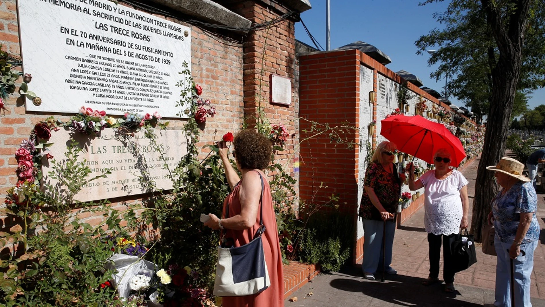 Una mujer coloca una rosa en el muro dedicado a las 'Trece Rosas'