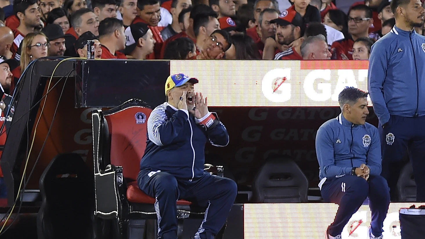 Maradona da instrucciones sentado en su trono