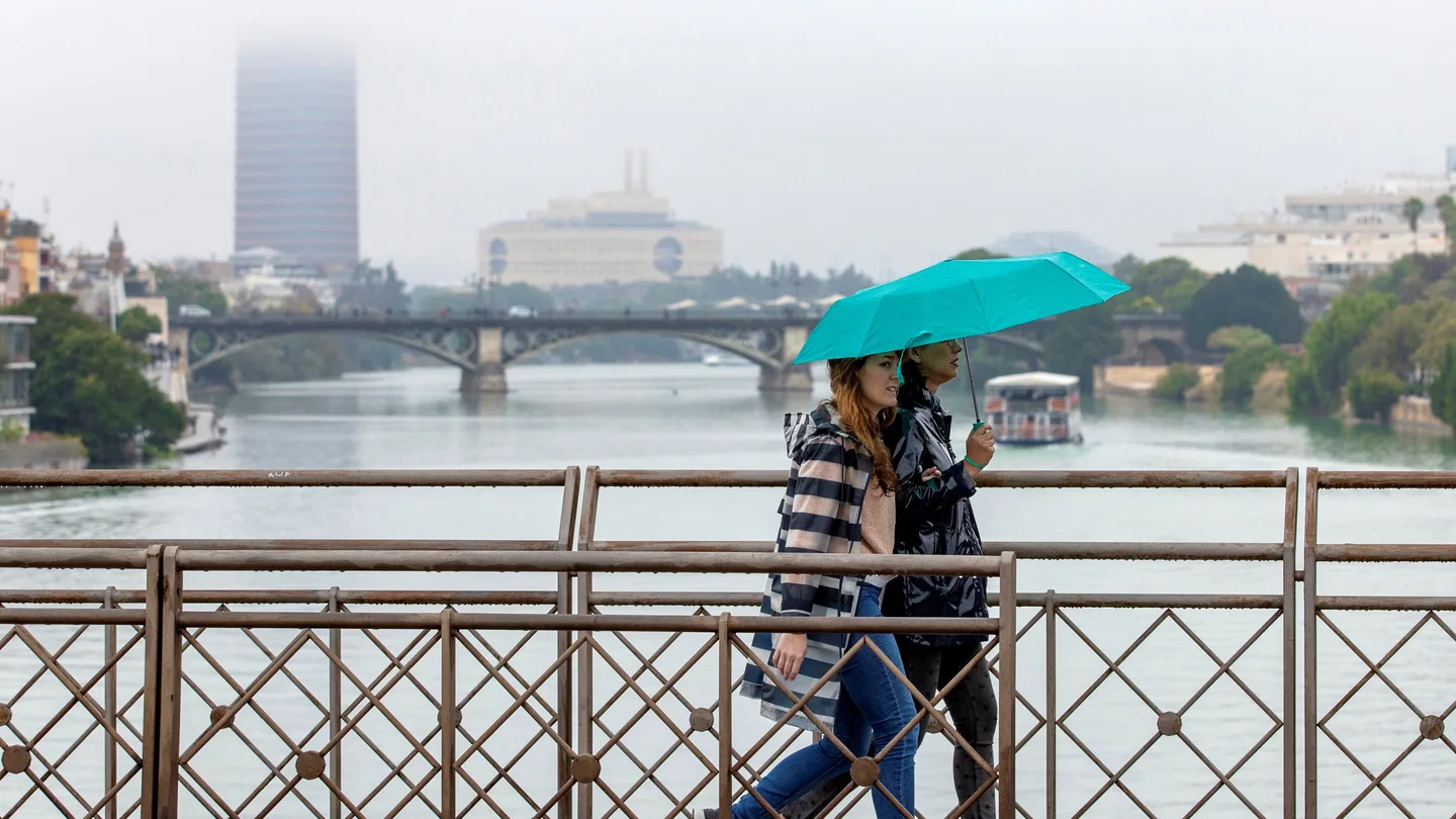 Dos personas atraviesan el puente de San Telmo, con el puente de Triana y Torre Sevilla. Dos personas atraviesan el puente de San Telmo, con el puente de Triana y Torre Sevilla.