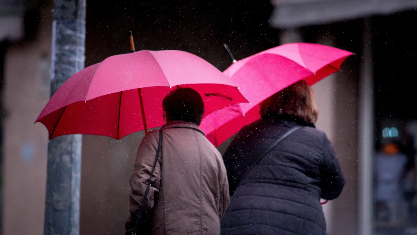 Dos mujeres ser protegen de la lluvia. Dos mujeres ser protegen de la lluvia en las calles de Ourense, Galicia