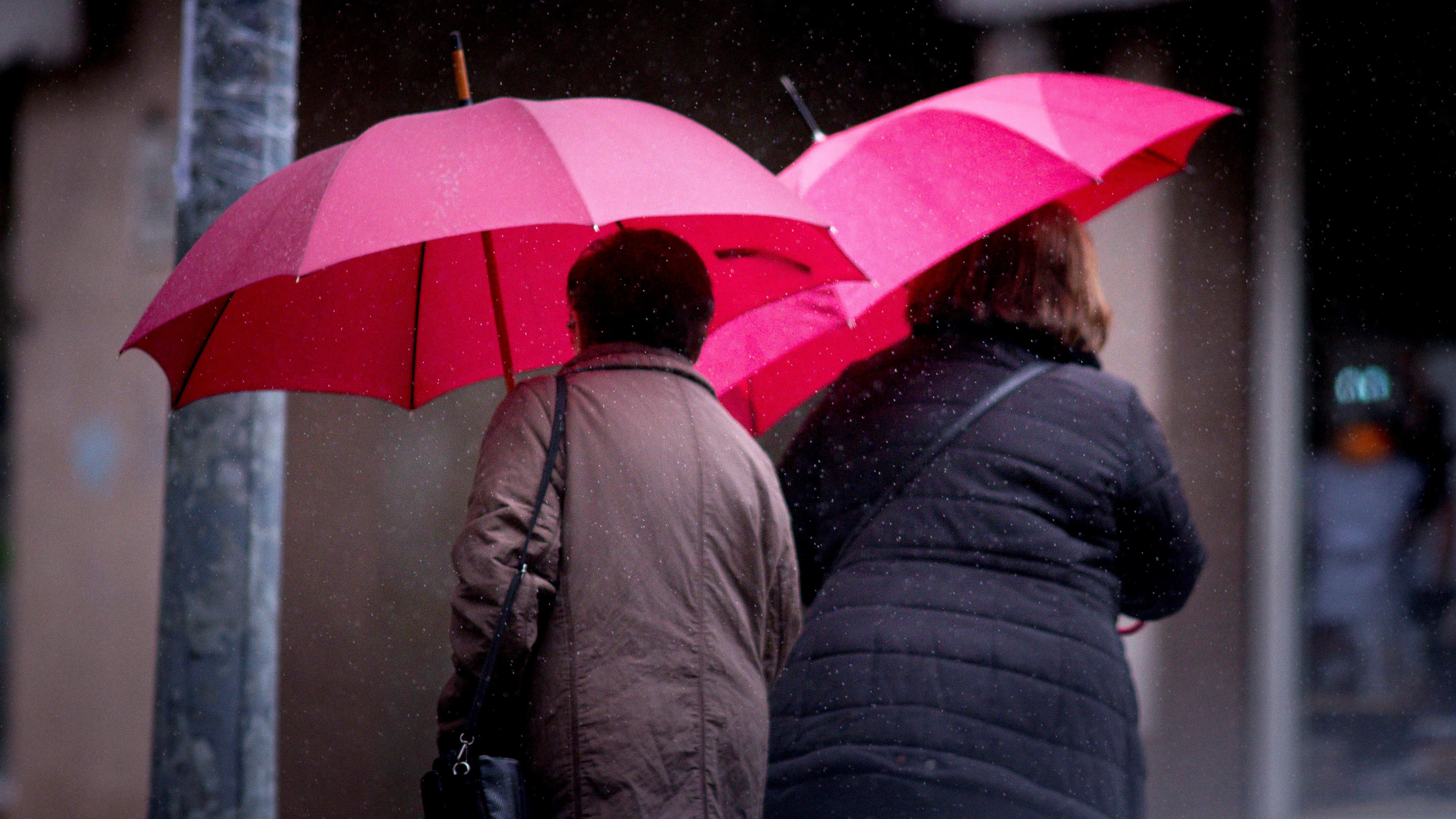 Dos mujeres ser protegen de la lluvia en las calles de Ourense, Galicia