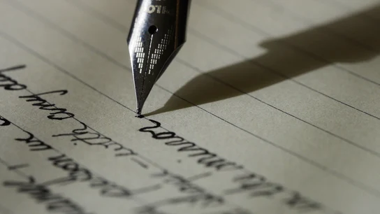 Imagen de archivo de una pluma escribiendo una nota Imagen de archivo de una pluma escribiendo una nota