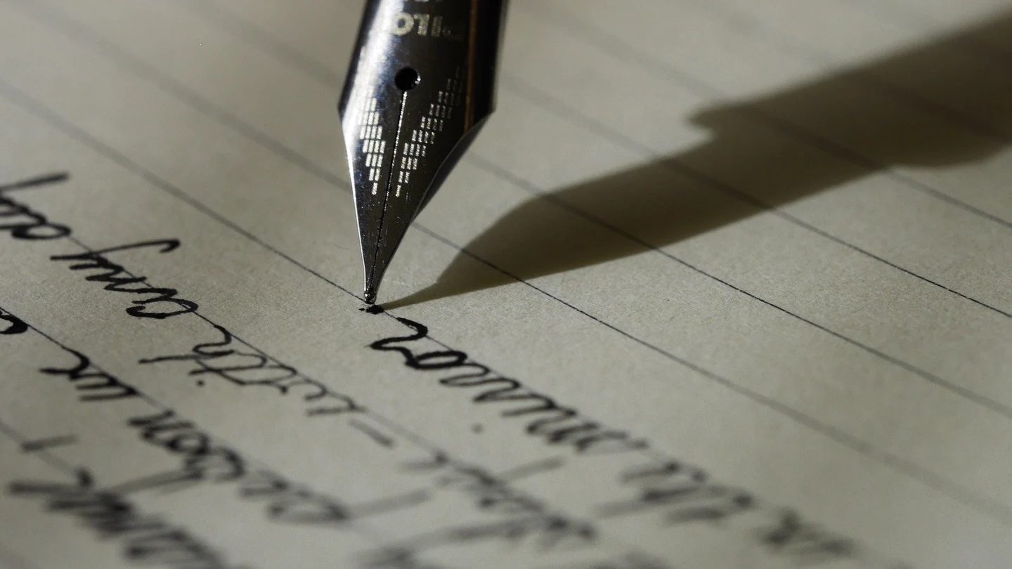 Imagen de archivo de una pluma escribiendo una nota Imagen de archivo de una pluma escribiendo una nota