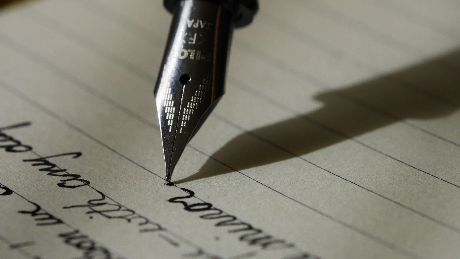 Imagen de archivo de una pluma escribiendo una nota