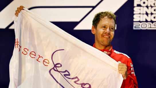 Vettel sostiene una bandera con el lema 'Essere Ferrari' ('Ser Ferrari') Vettel sostiene una bandera con el lema 'Essere Ferrari' ('Ser Ferrari')