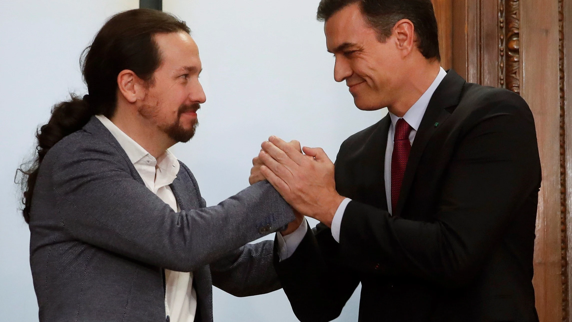 Pablo Iglesias y Pedro Sánchez se estrechan la mano sonrientes