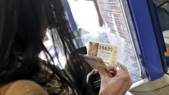 Una mujer compra varios décimos en una administración de Lotería Una mujer compra varios décimos en una administración de Lotería