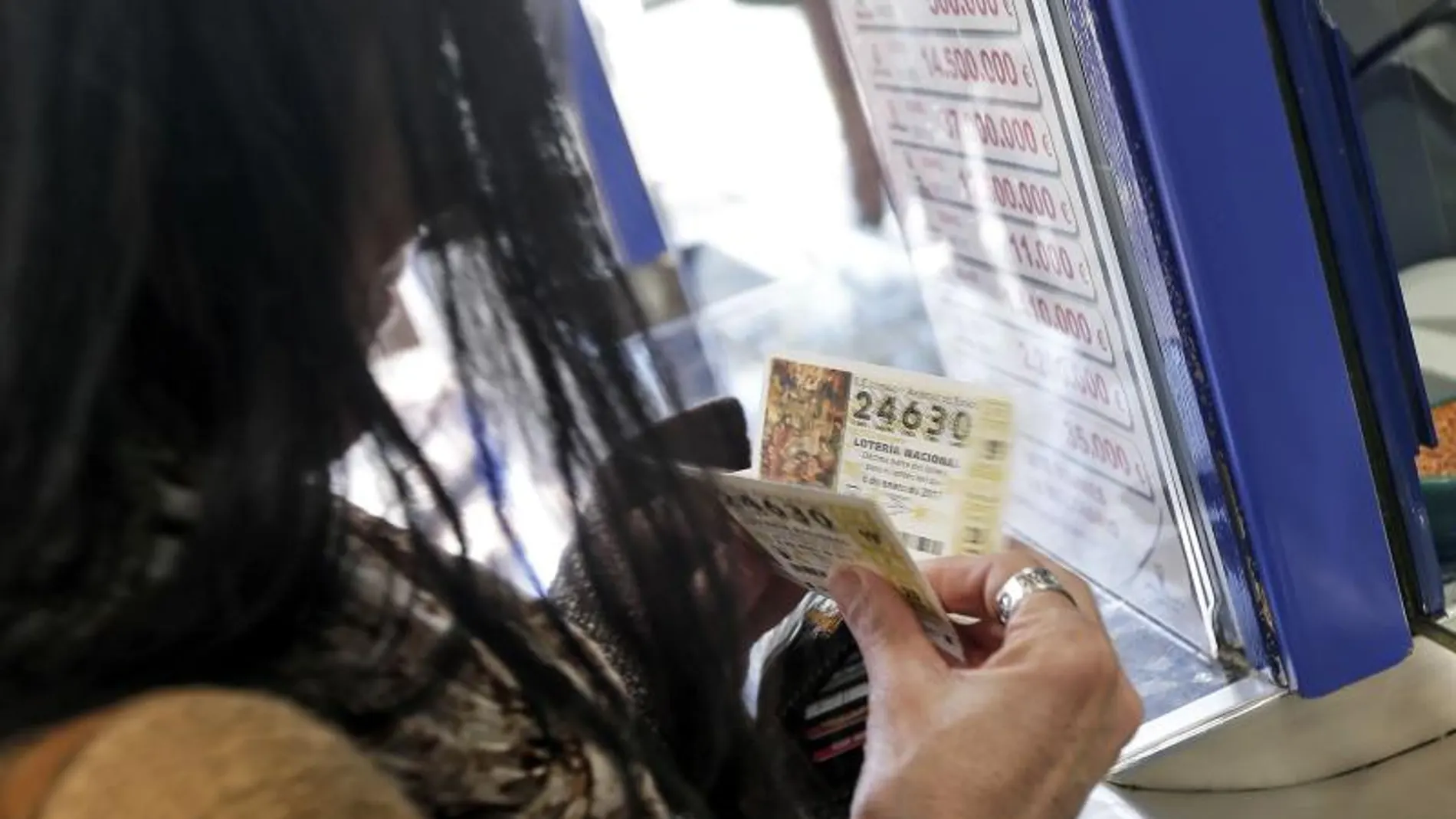 Una mujer compra varios décimos en una administración de Lotería